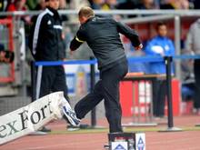 Braunschweigs Trainer Torsten Lieberknecht lässt seine Wut auch mal an einer Werbebande aus. Foto: Peter Steffen