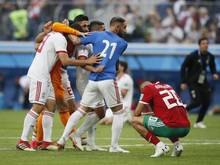 Der Marokkaner Aziz Bouhaddouz (r.) hockt nach seinem Eigentor auf dem Rasen, während die Spieler des Iran den Sieg bejubeln