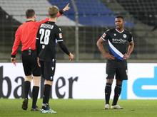 Schiedsrichter Markus Schmidt zeigt Bielefelds Abwehrspieler Nathan De Medina (r.) nach der Roten Karte, das Spielfeld zu verlassen