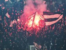 Fans von Besiktas stehen hinter einem Zaun auf der Tribüne und zünden Pyrotechnik