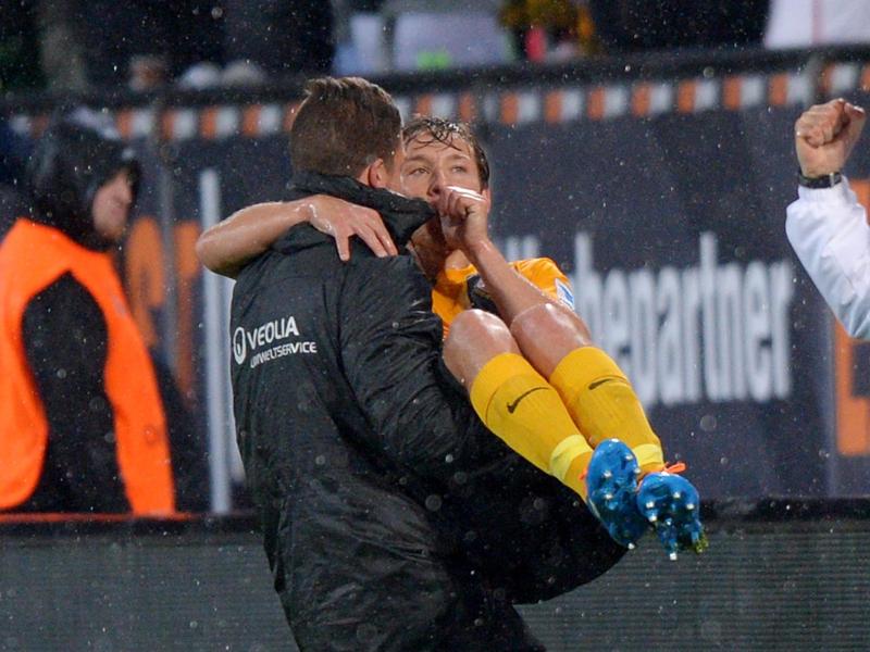 Dynamo-Torwart Florian Fromlowitz (l.) trägt den Doppeltorschützen Robert Koch auf dem Arm
