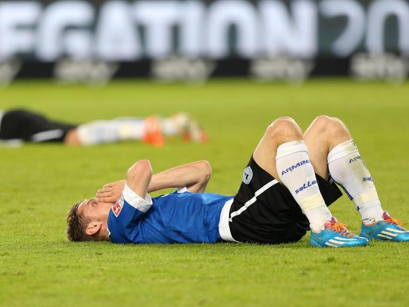 Spieler von Arminia Bielefeld liegen bei Spielschluss enttäuscht auf dem Rasen