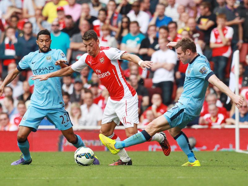 Arsenals Mesut Özil (m.) setzt sich gegen Gael Clichy (l.) und James Milner von Manchester City durch