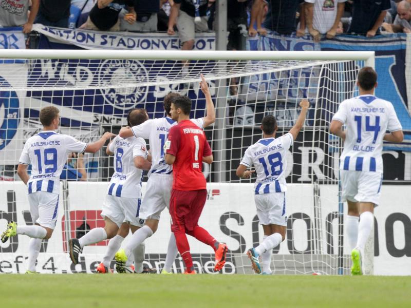 Die Karlsruher bejubeln das 2:1 gegen Frankfurt, während FSV-Keeper André Weis (M.) den Kopf hängen lässt