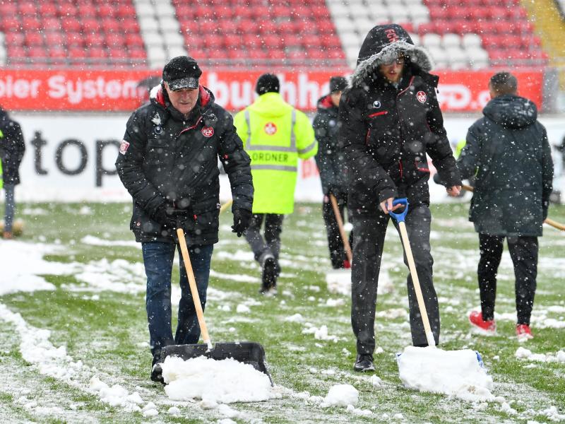 Mitarbeiter räumen das Spielfeld in Kaiserslautern vom Schnee
