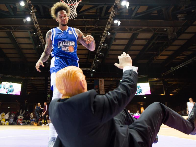 Julian Gamble von den Telekom Baskets Bonn dunkt über einen als Donald Trump kostümierten Mann Julian Gamble von den Telekom Baskets Bonn dunkt über einen als Donald Trump kostümierten Mann
