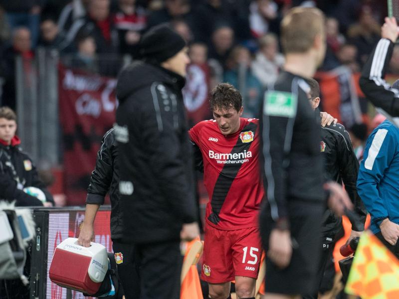 Leverkusens Julian Baumgartlinger (M,hinten) wird verletzt vom Platz begleitet. Foto: Bernd Thissen