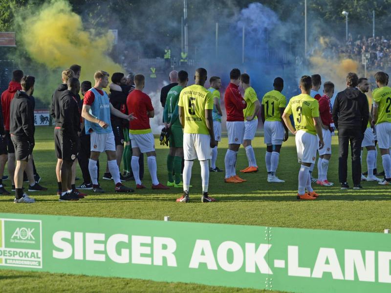 Die Cottbusser beobachten nach dem Pokalsieg die Pyroaktionen der Babelsberger Fans.