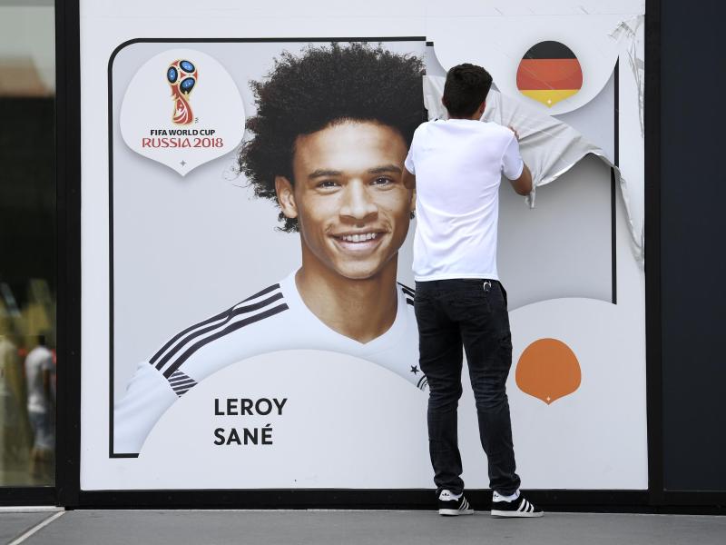 Ein Mitarbeiter zieht eine Folie mit dem Porträt von Leroy Sané von der Außenwand des Fußballmuseums ab