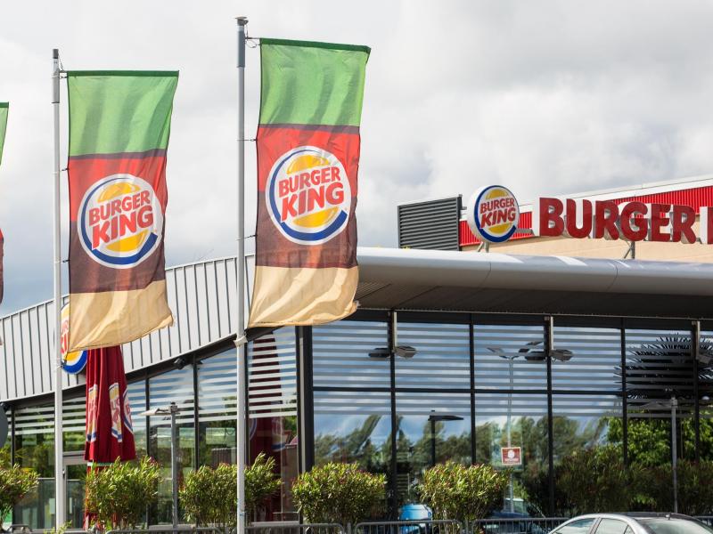 Flaggen der Fast-Food-Kette Burger King wehen neben einer Filiale im Wind