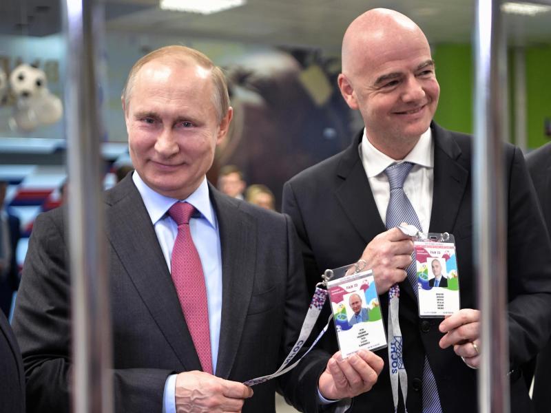Russlands Präsident Wladimir Putin (l) und FIFA-Präsident Gianni Infantino zeigen beim Betreten eines Stadions ihre Fan-ID