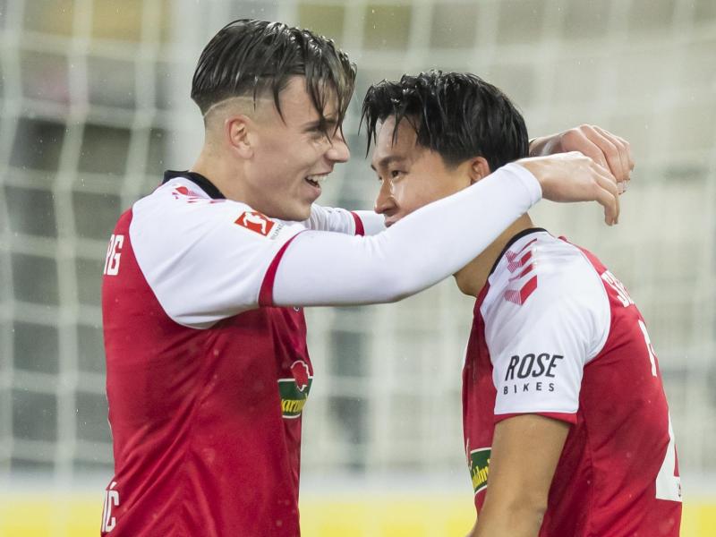 Woo-yeong Jeong (r) und Ermedin Demirovic feiern ein Tor für den SC Freiburg