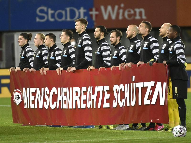 Die österreichische Nationalmannschaft hält vor Spielbeginn ein Banner mit der Aufschrift «Menschenrechte schützen» hoch