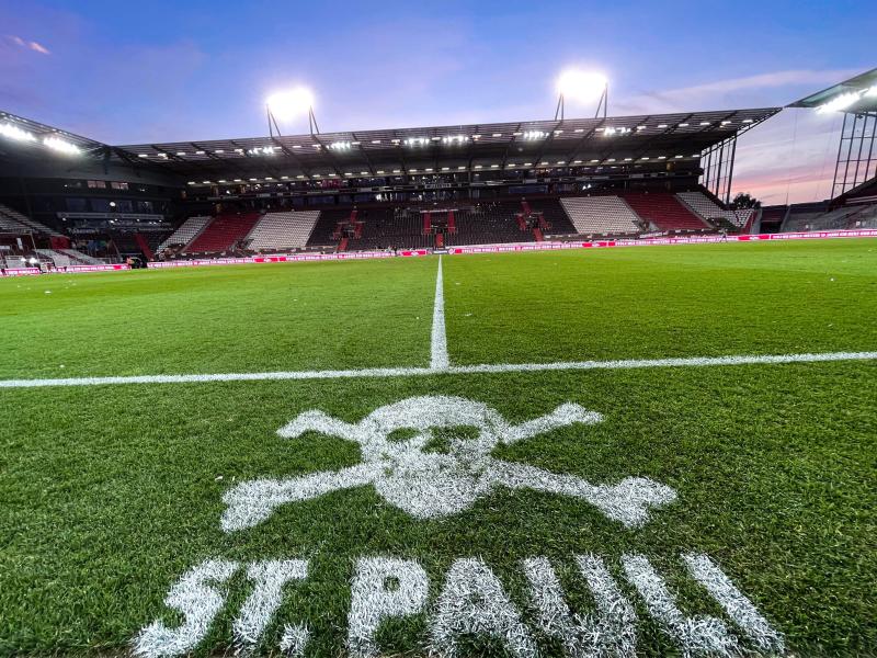Das Logo von St.Pauli ist an der Mittellinie vor den Trainerbänken auf den Rasen des Millerntorstadions gesprüht