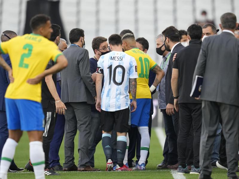 Lionel Messi (M,l) und Neymar (M,r) unterhalten sich, während das Spiel von den Gesundheitsbehörden unterbrochen wird