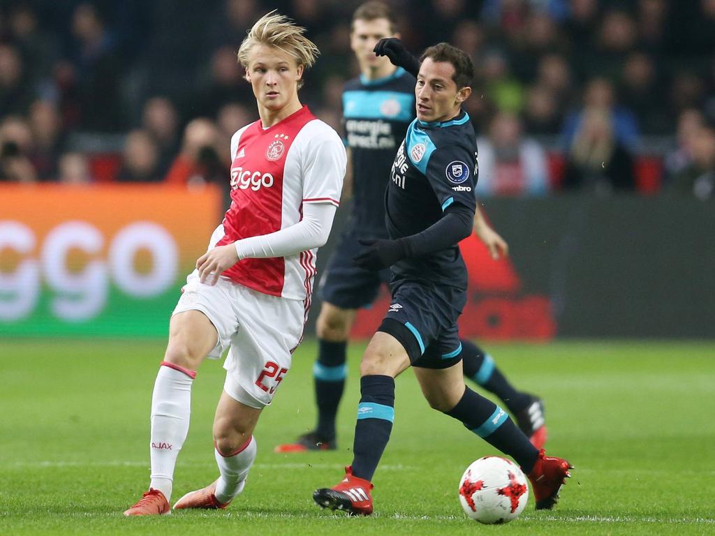 Andrés Guardado (r.) geeft in de eerste minuten van de wedstrijd tussen Ajax en PSV met zijn knie een tikje op het bovenbeen van Kasper Dolberg (l.). (18-12-2016)