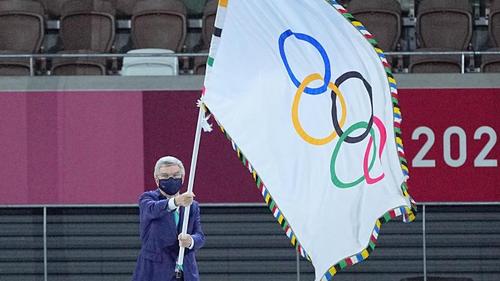 IOC-Präsident Thomas Bach hält die Fahne olympische Fahne hoch