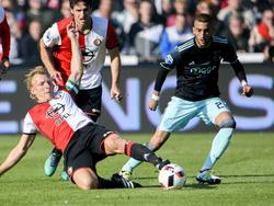 Feyenoord-aanvoerder Dirk Kuyt speelt de bal weg voor de voeten van Ajacied Hakim Ziyech (r.). Op de achtergrond kijkt Eric Botteghin mee. (23-10-2016)