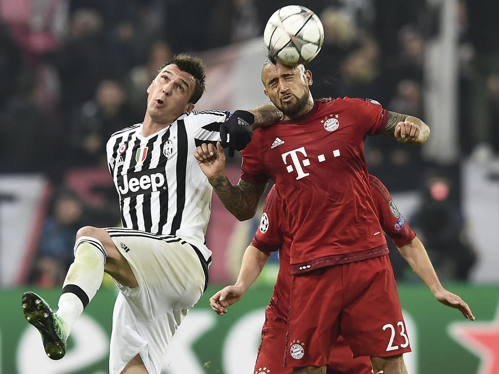 De grote Mario Mandžukić (l.) en de wat kleinere Arturo Vidal (r.) zijn in een kopduel verwikkeld tijdens de Champions League-wedstrijd Juventus - Bayern München. Het is de Chileen die het kopduel opvallend genoeg wint. (23-02-2016)