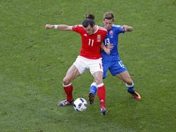 Gareth Bale (l.) vecht een duel uit met Patrik Hrošovský (r.) tijdens het EK-duel Wales - Slowakije (11-06-2016).