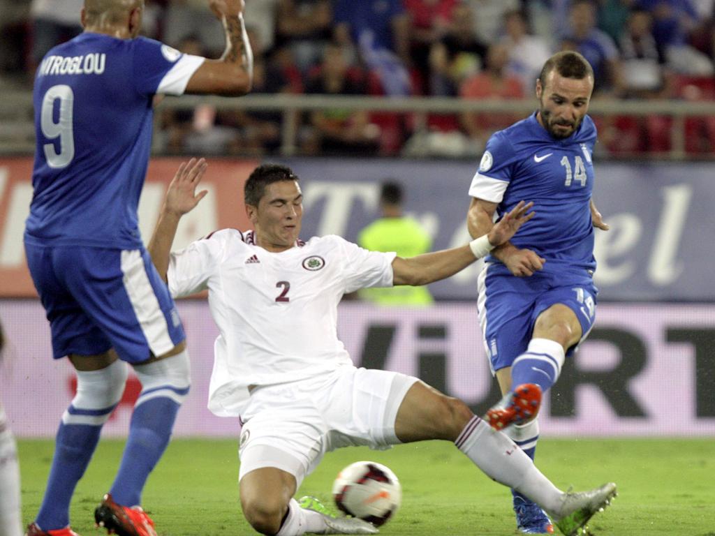 Vitālijs Maksimenko probeert met een sliding het schot van Dimitrios Salpingidis (r.) te blokkeren tijdens het WK-kwalificatieduel Griekenland - Letland. (10-09-2013)