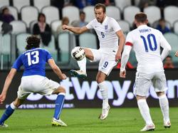 Harry Kane (m.) probeert tijdens de oefeninterland tussen Italië en Engeland Andrea Ranocchia (l.) te omspelen, door Wayne Rooney te bereiken met een balletje breed. (31-03-2015)