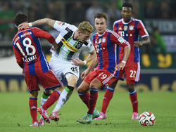 Borussia Mönchengladbachs André Hahn (M.) tankt sich gegen Bayern Münchens Juan Bernat (l.) und Mario Götze durch