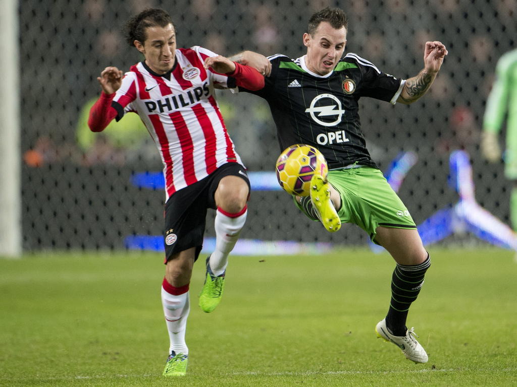Andrés Guardado (l.) en Luke Wilkshire (r.) doen een poging om de bal te winnen tijdens PSV - Feyenoord. (17-12-2014)