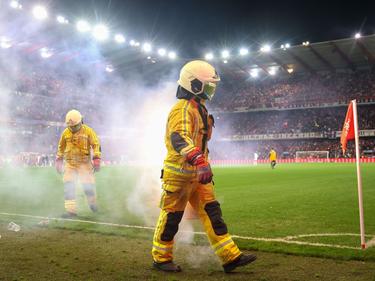 Feuerwehrleute löschen Bengalische Feuer während des Fußballspiels