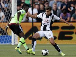 Ajax-aanvaller Bertrand Traoré (l.) speelt de bal subtiel door de benen van Heracles Almelo-verdediger Justin Hoogma (r.). (18-09-2016)