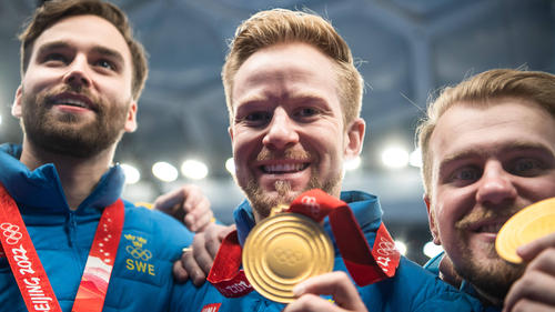 Niklas Edin (m.) feiert mit seinen Teamkollegen den Olympiasieg