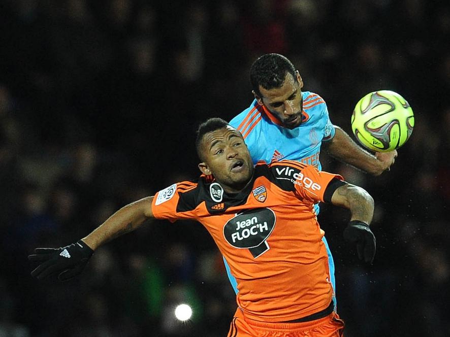 Jordan Ayew (l.) vecht een luchtduel uit met Romao (r.) tijdens het competitieduel FC Lorient - Olympique Marseille. (02-12-2014)