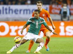 Giovani Dos Santos (l.) wordt aangespeeld en hij houdt keurig zijn lichaam tussen de bal en verdediger Joël Veltman (r.) in de oefeninterland Nederland - Mexico. (14-11-2014)