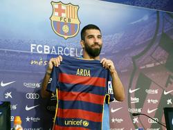 Arda Turan houdt het nieuwe thuisshirt van FC Barcelona omhoog tijdens zijn officiële presentatie aan de pers. (10-07-2015)