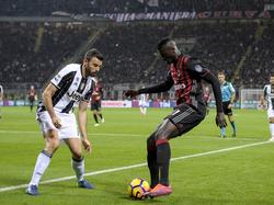 AC Milan-aanvaller M'Baye Niang dribbelt af op Juventus-verdediger Andrea Barzagli, die goed naar de bal blijft kijken. (22-10-2016)