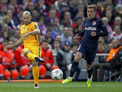 Javier Mascherano (l.) van Barcelona speelt de bal voordat Antoine Griezmann erbij kan komen. (13-04-2016)