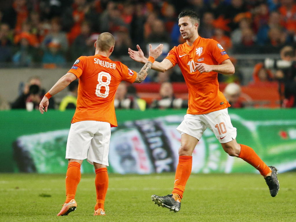 Robin van Persie (r.) wordt in de wedstrijd Nederland - Letland vervroegd naar de kant gehaald. Wesley Sneijder connect nog even met de spits. (16-11-2014)