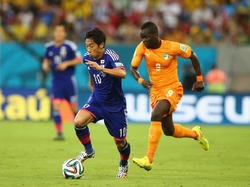 Shinji Kagawa (l.) probeert Cheick Tioté (r.) voor te blijven tijdens Ivoorkust - Japan. (15-6-2014)