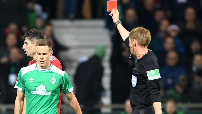 Schiedsrichter Christian Dingert (r) zeigt Werders Niklas Moisander die Gelb-Rote Karte