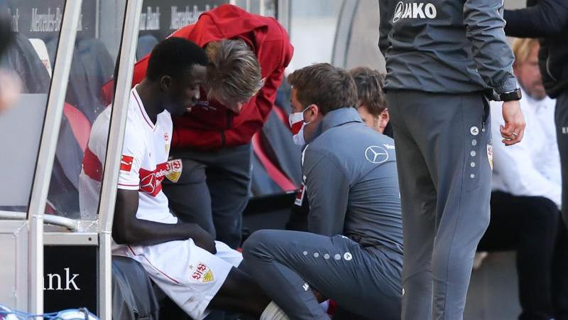 Silas Wamangituka (l.) vom VfB Stuttgart sitzt verletzt auf der Ersatzbank
