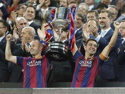 Iniesta (l.) en Xavi houden samen de Copa del Rey omhoog na de overwinning van FC Barcelona in de finale tegen Athletic Bilbao. (30-05-2015)