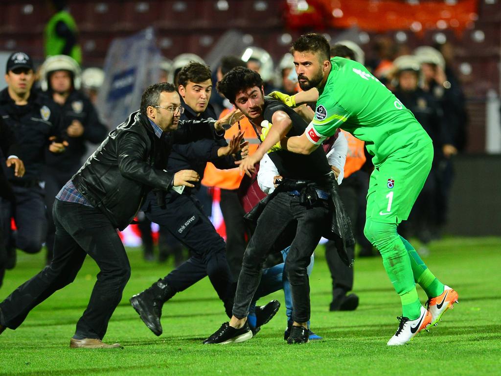 Trabzonspor-Keeper Kivrak (r.) hilft, einen Fan dingfest zu machen, der zuvor auf einen der Assistenten eingeprügelt hatte