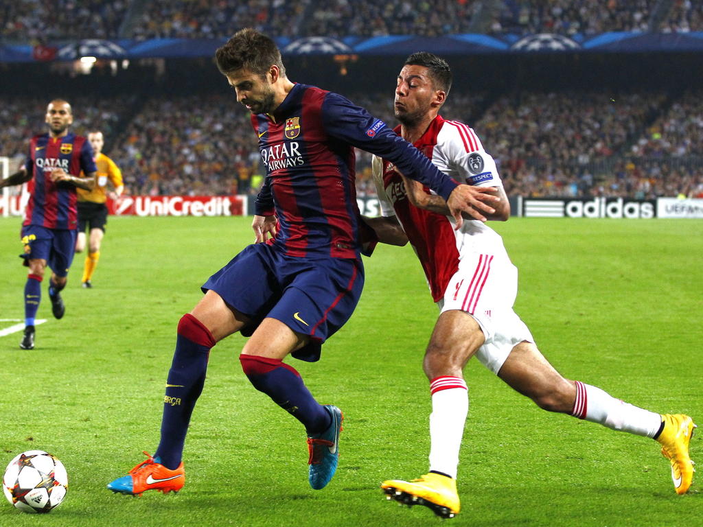 Gerard Piqué (l.) heeft geen problemen met het afhouden van Ricardo Kishna (r.) tijdens het Champions League-duel FC Barcelona - Ajax. (21-10-2014)