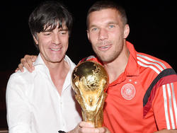 Lukas Podolski (r.), Joachim Löw und der WM-Pokal