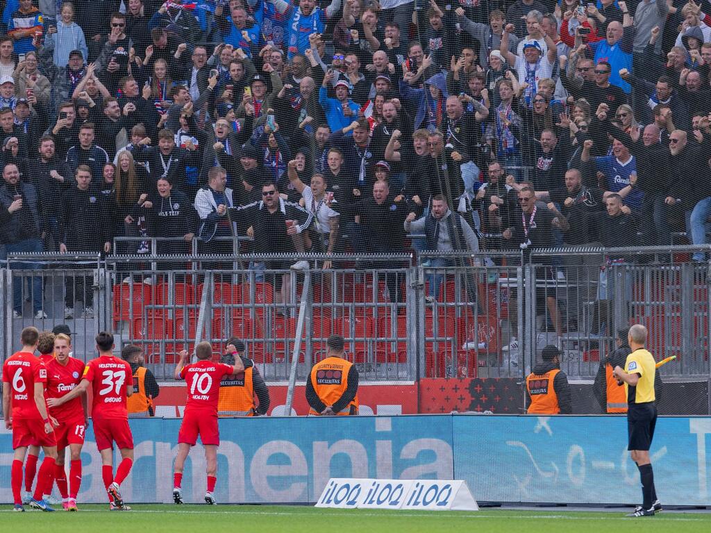 Die Spieler von Holstein Kiel freuen sich mit ihren Fans über einen unerwarteten Punkt bei Bayer Leverkusen