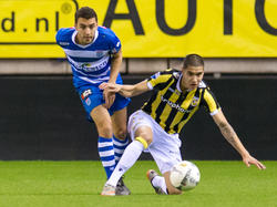 Een duel tussen twee verdedigers. PEC Zwolle-aanvoerder Bram van Polen (l.) kan niet voorkomen dat Vitesse-talent Kevin Diks (r.) de bal net voor hem weg speelt. (27-01-2016)