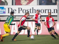 Dirk Kuyt (m.) neemt de bal mee op het middenveld, terwijl Kevin Jansen (l.) druk probeert te zetten op de veteraan. (01-11-2015)
