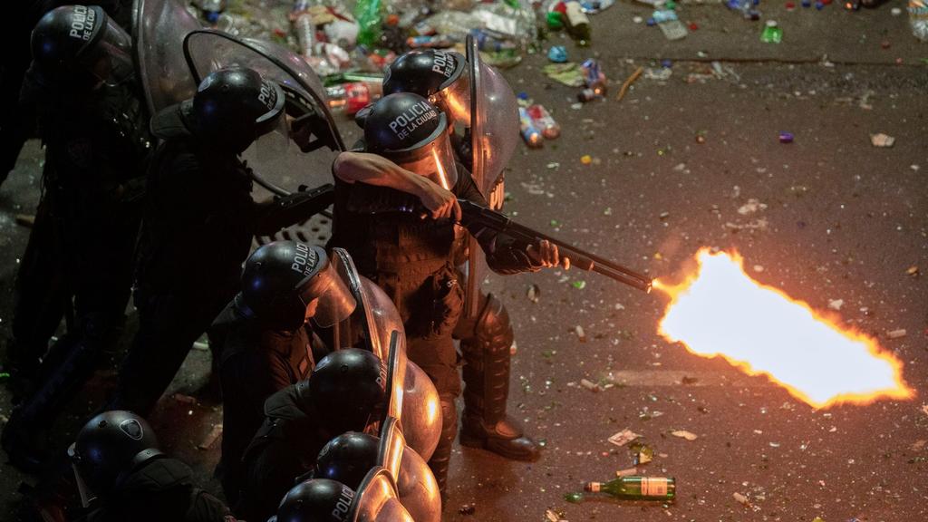 Ein Polizist der argentinischen Bereitschaftspolizei feuert eine Schrotflinte, nachdem eine Parade zur Feier der Weltmeister in Buenos Aires abrupt abgebrochen wurde