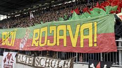 Fans von St. Pauli halten ein Banner mit dem Schriftzug "Biji Rojava" ("Es lebe Rojava") in die Höhe