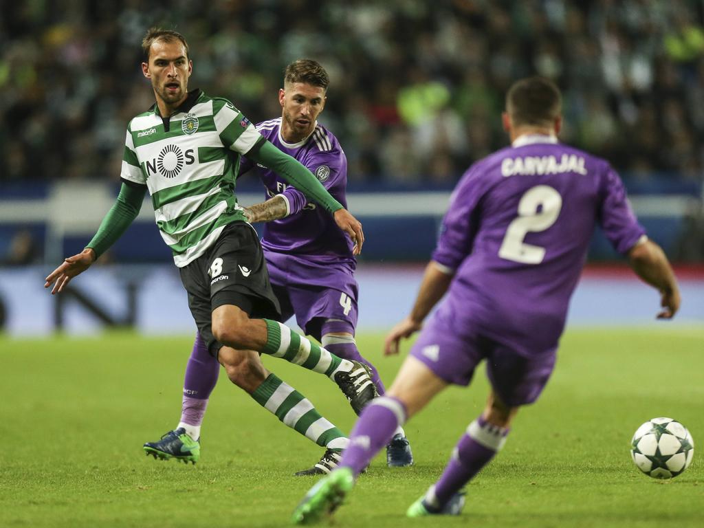 Sporting CP-spits Bas Dost (r.) kaatst de bal terug terwijl hij onder druk wordt gezet door Real Madrid-verdediger Sergio Ramos (m.). (22-11-2016)